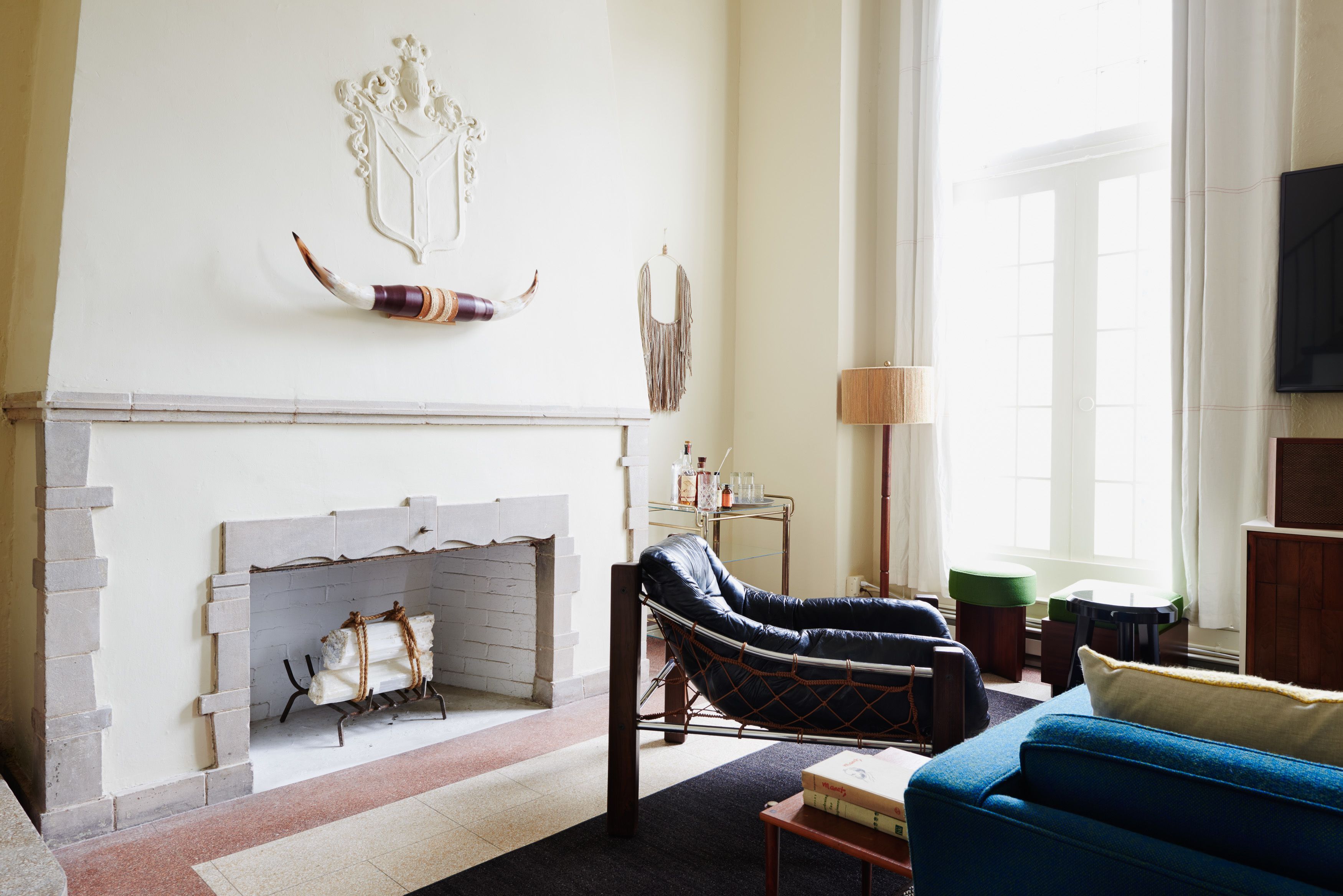 A living room with a fireplace, a blue sofa, and a leather armchair.