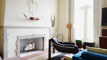 Una sala de estar con chimenea, un sofá azul y un sillón de cuero.