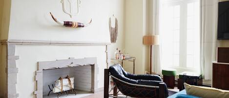 A living room with a fireplace, a blue sofa, and a leather armchair.