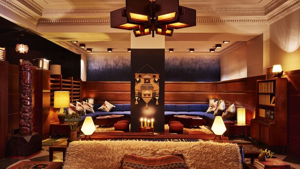 A luxurious hotel lobby with a plush sofa set, a large wooden bookshelf, and a central decorative pillar.