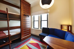 A room with bunk beds, a sofa, a table, and a lamp. - Freehand Chicago (Chicago)
