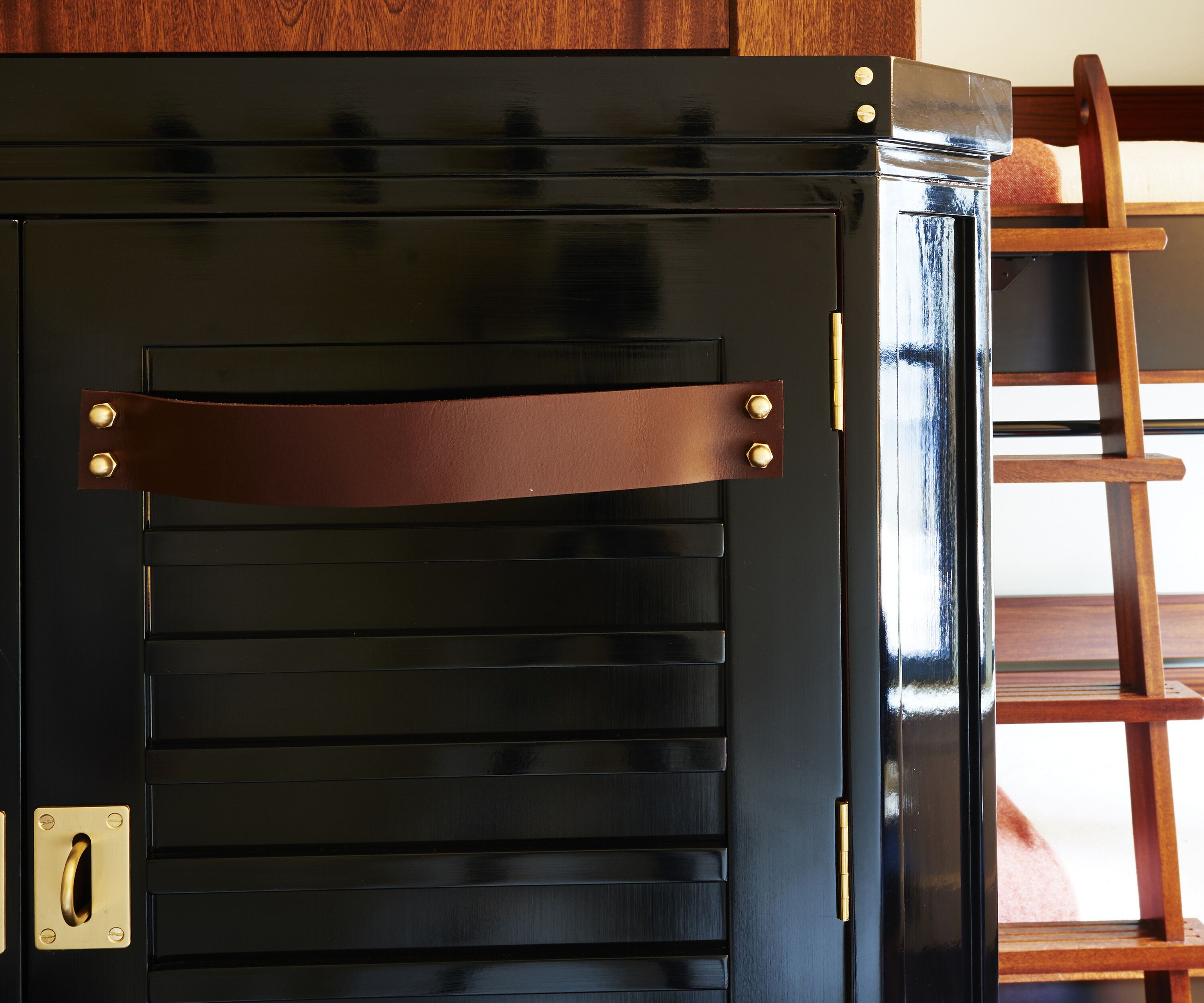 Una porta nera con listelli orizzontali e una tracolla in pelle marrone.