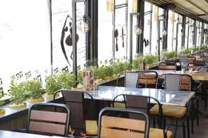 A restaurant with long tables, chairs, and potted plants. - Ramada by Wyndham Elazig (Elazig)