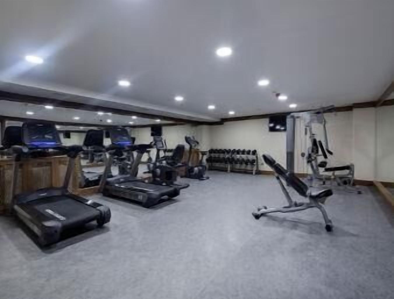 Une salle de sport équipée de tapis de course, de vélos elliptiques et de bancs de musculation.