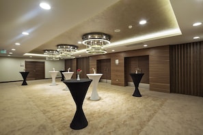 A spacious room with multiple round tables, some with black and white tablecloths, and a modern chandelier. - Ramada by Wyndham Elazig (Elazig)