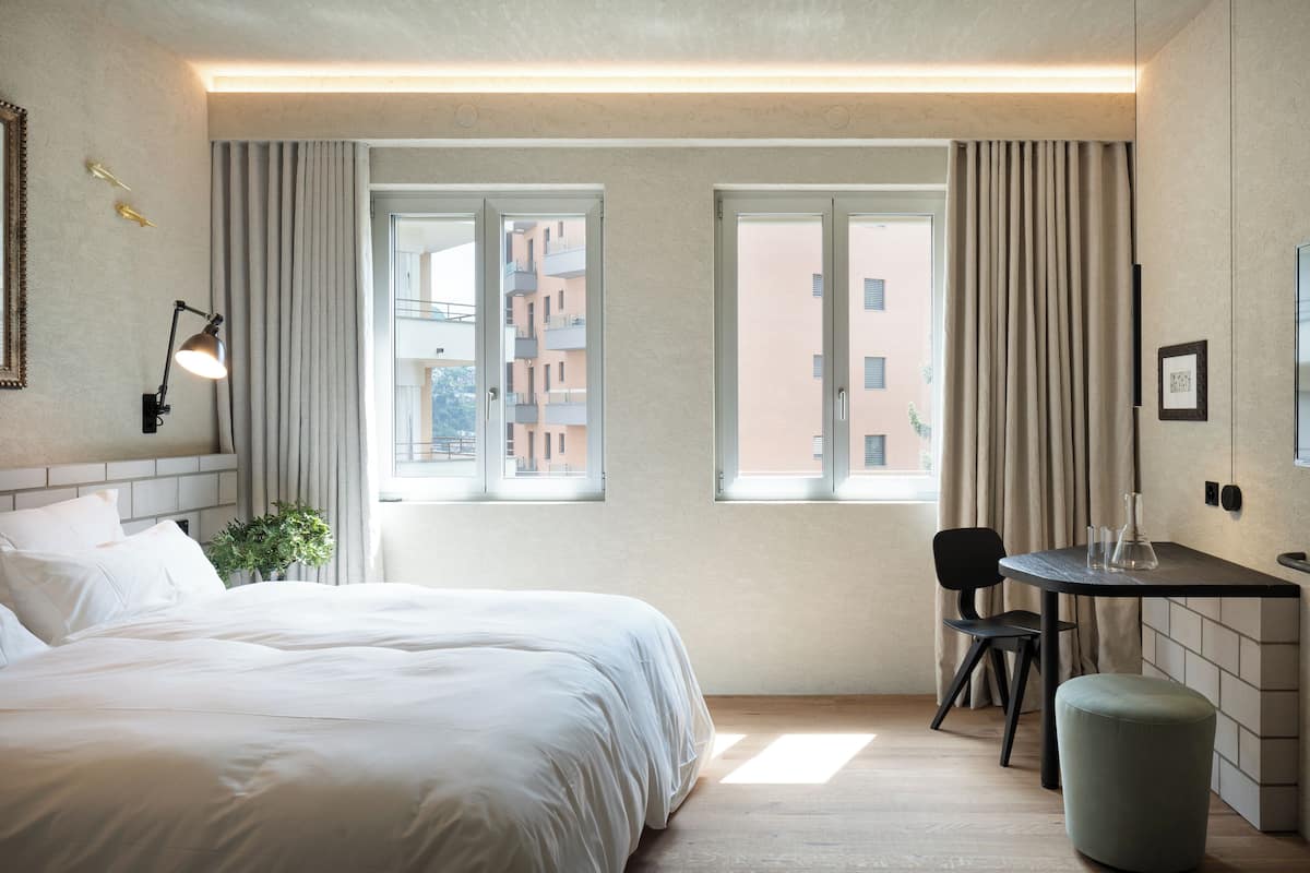 Een hotelkamer met een bed, een bureau, een stoel en een raam met gordijnen.