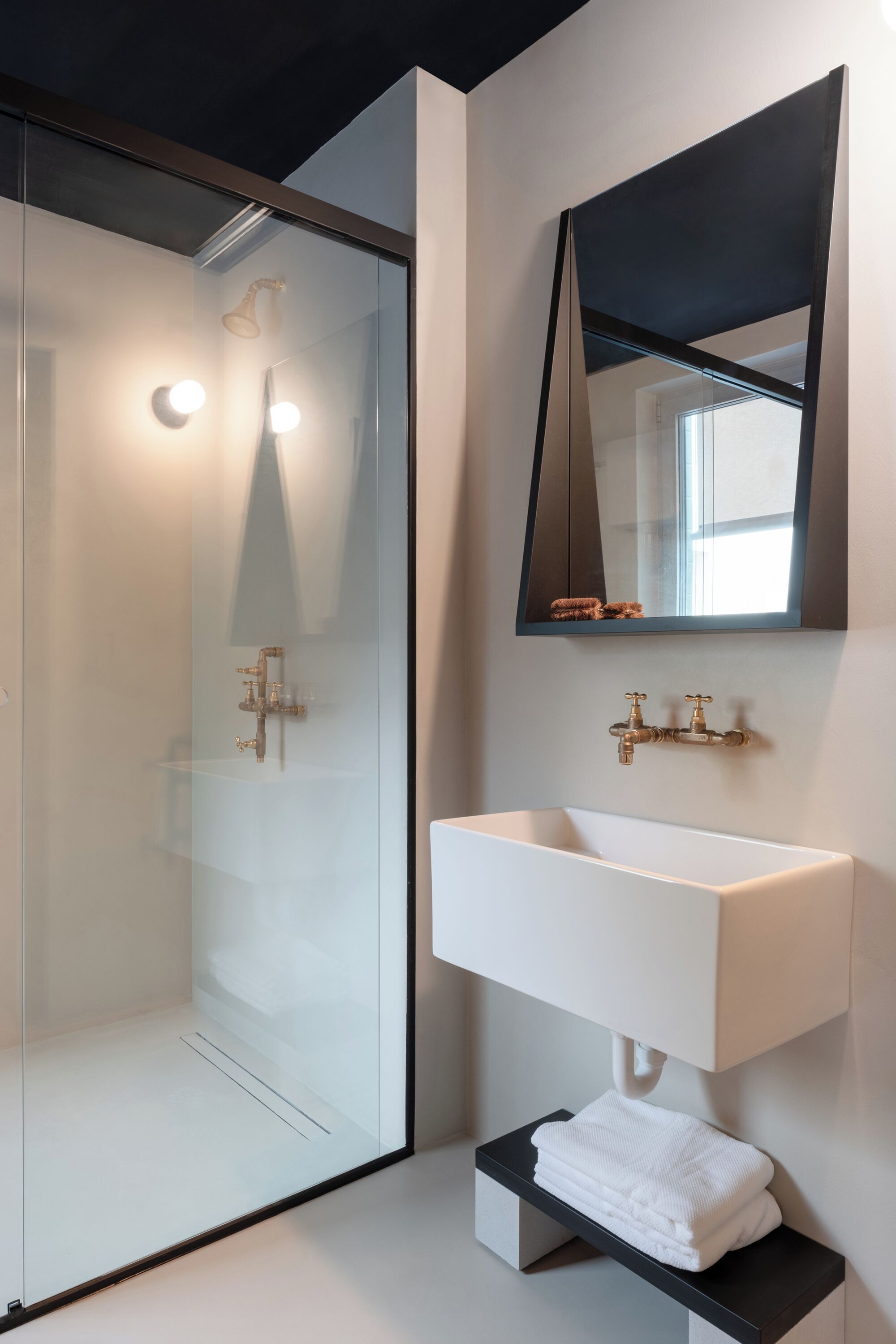 A modern bathroom with a glass shower enclosure, a white sink, and a large mirror.