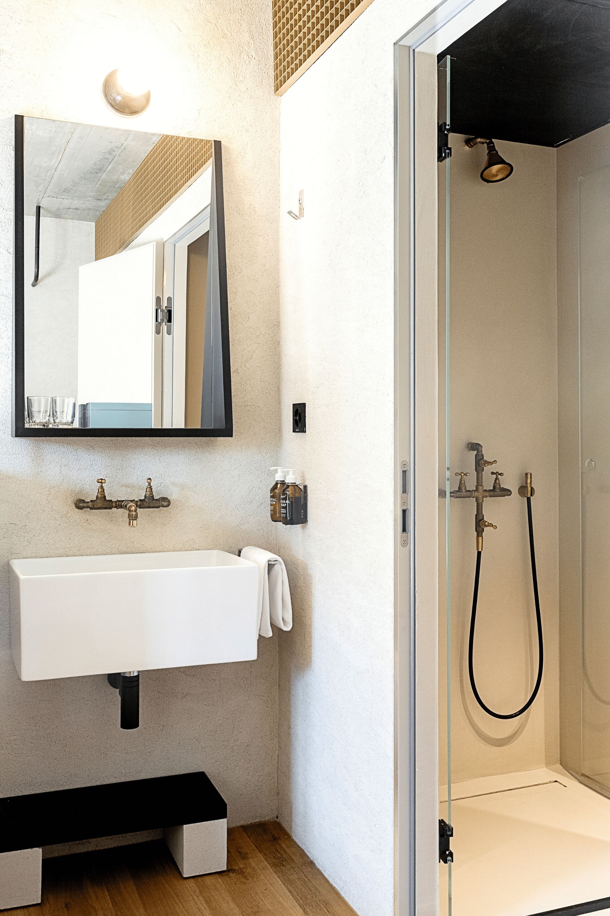 Une salle de bain avec un lavabo blanc, un miroir et une douche à parois de verre.