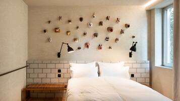 Un dormitorio moderno con un cabecero de ladrillo, un banco de madera y una pared decorada con diversas esculturas de cabeza de animales.