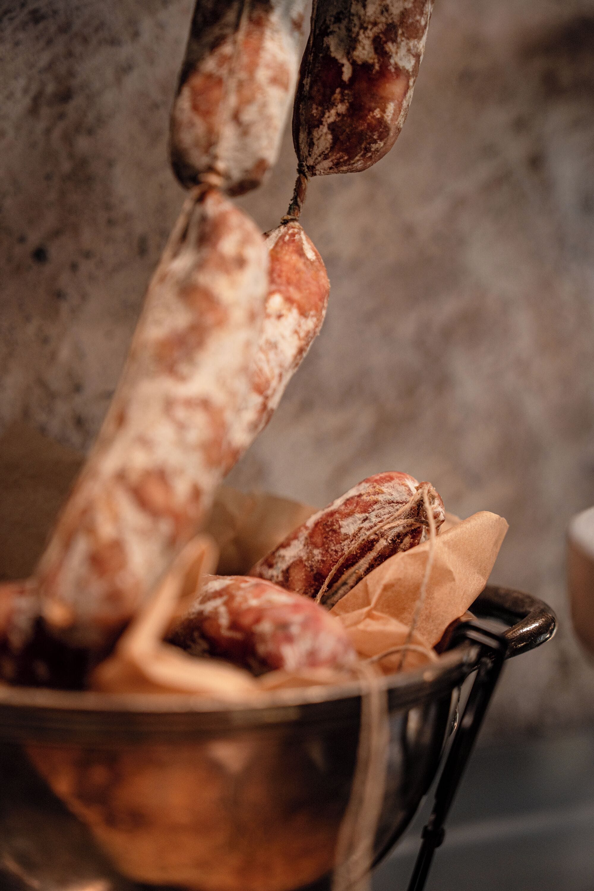 Un espositore di salumi con salsicce e un contenitore metallico pieno di pane.