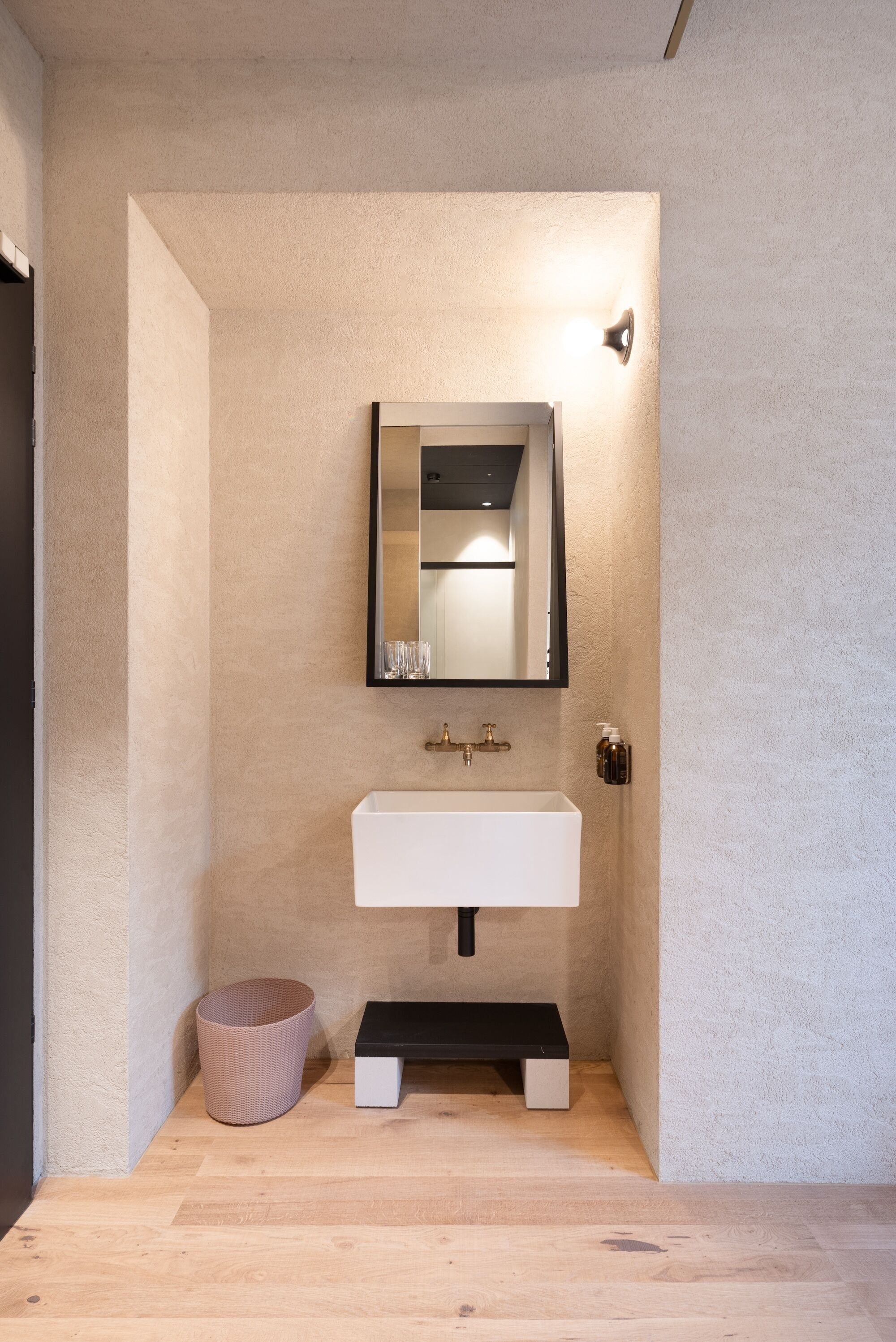 Une salle de bain moderne avec un lavabo blanc, un miroir et une petite poubelle.