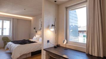 Et soveværelse med seng, sengebord, lampe og et vindue med gardiner.