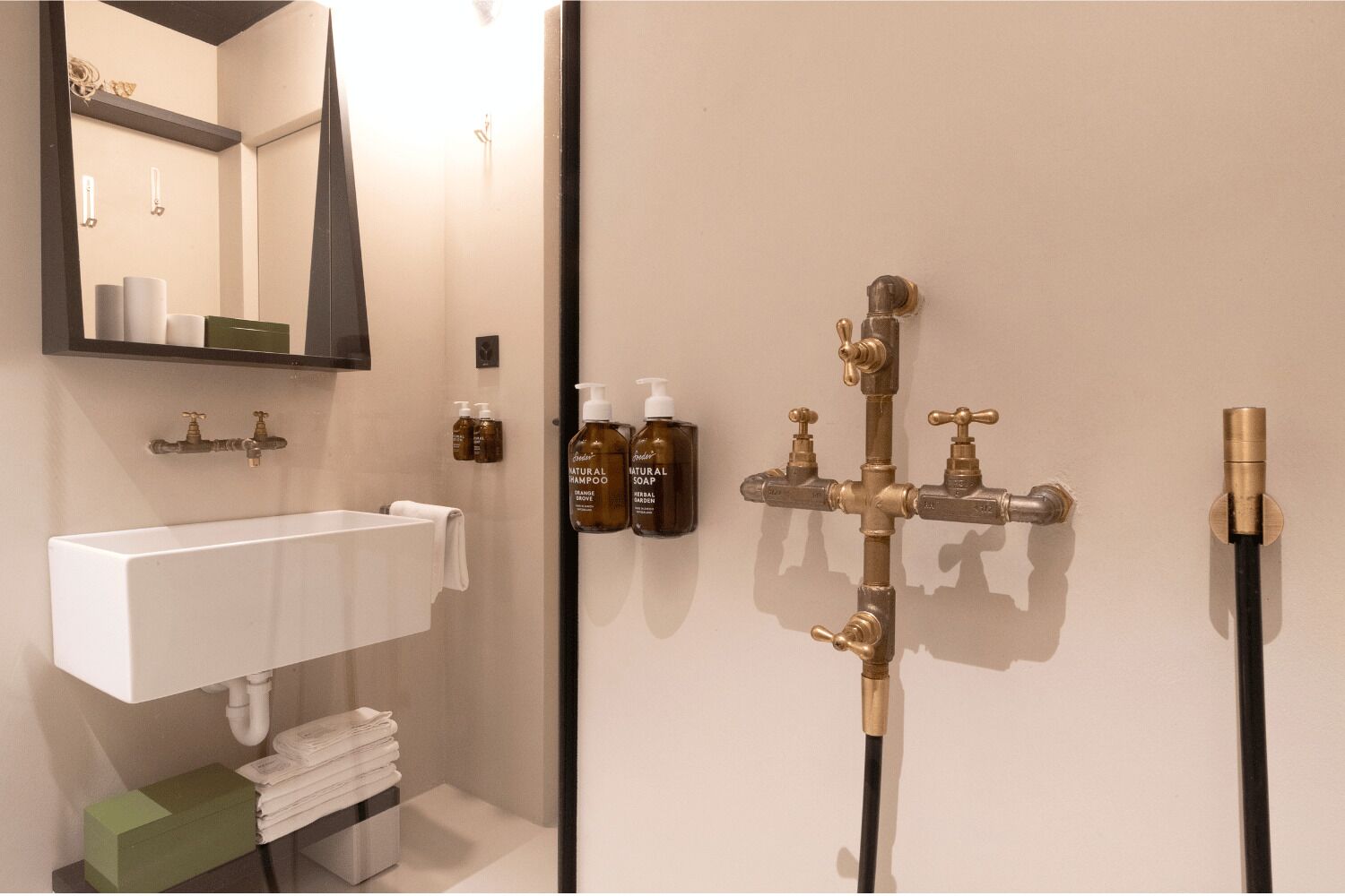 A bathroom with a white sink, a mirror, and a shower with multiple faucets.