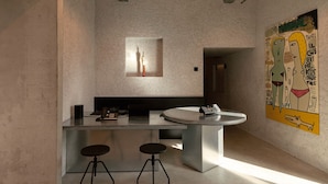 Una cocina moderna con una isla central, taburetes de bar y un cuadro abstracto grande en la pared.