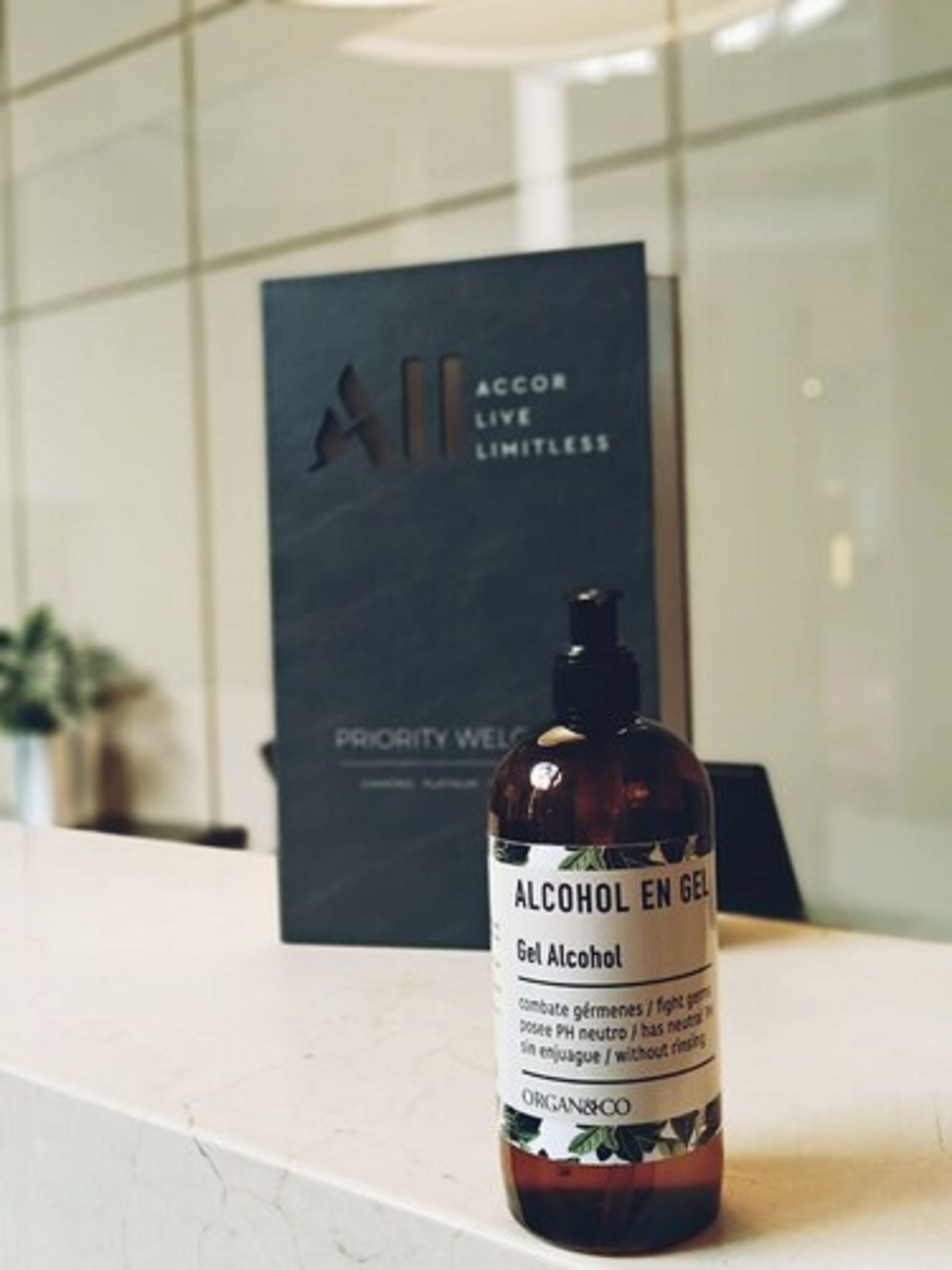A bottle of alcohol gel on a counter with a sign in the background.
