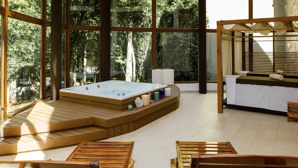 Un área de spa con hidromasaje, tumbonas de madera y una mesa de masaje.