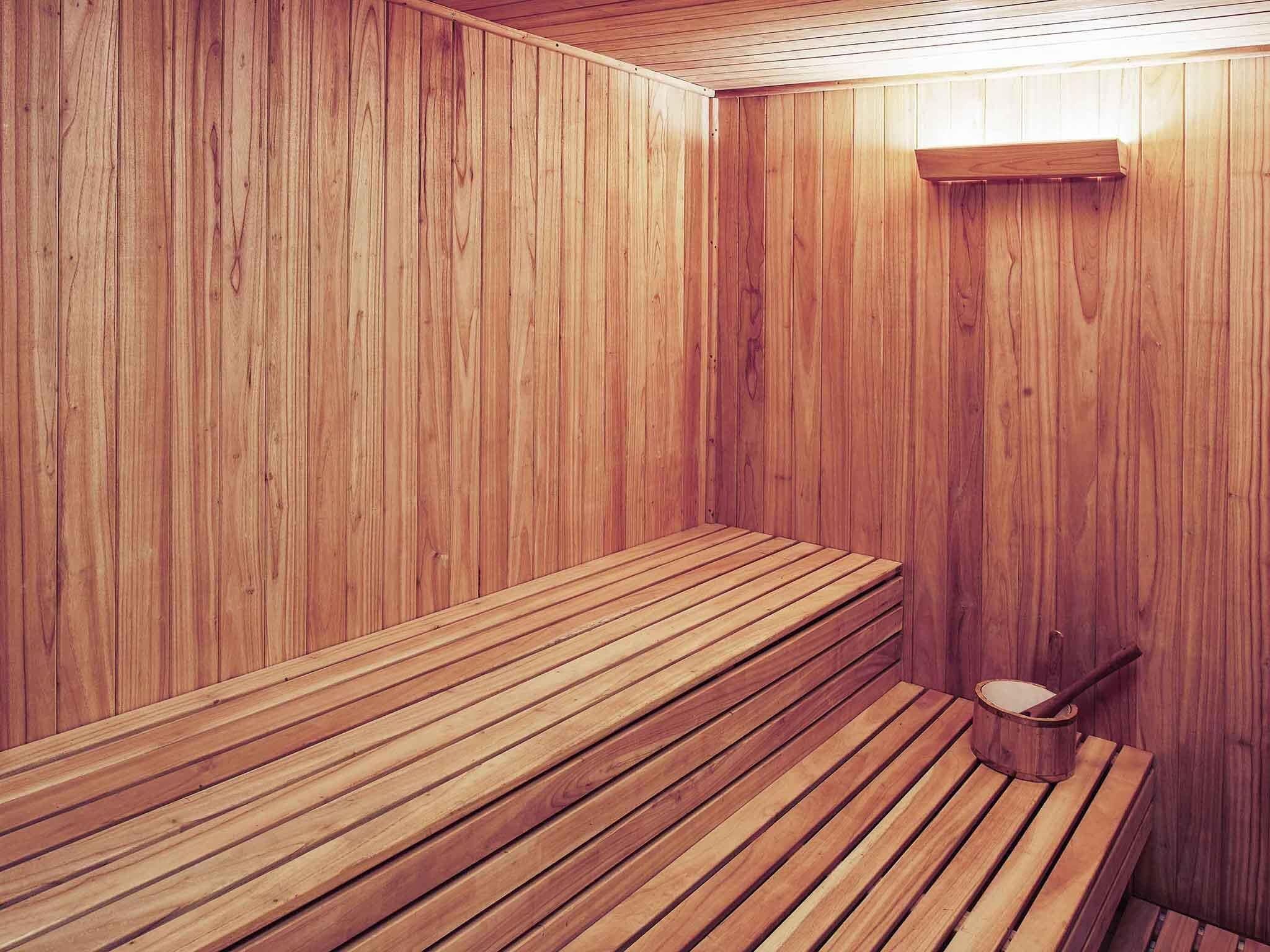 Una sauna con bancos de madera y un cubo de madera.