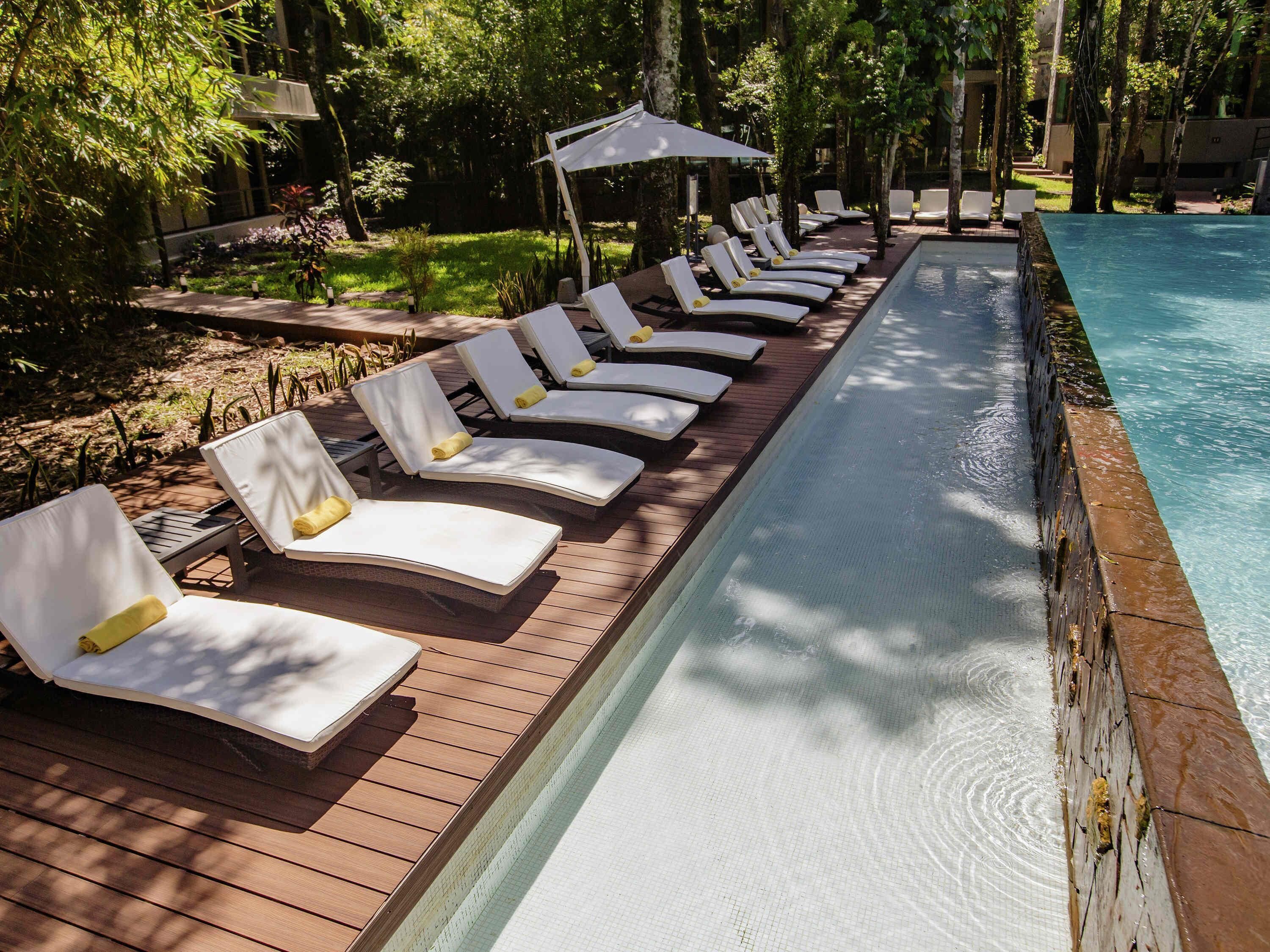 Un espace aménagé au bord de la piscine, avec des chaises longues et une terrasse en bois.