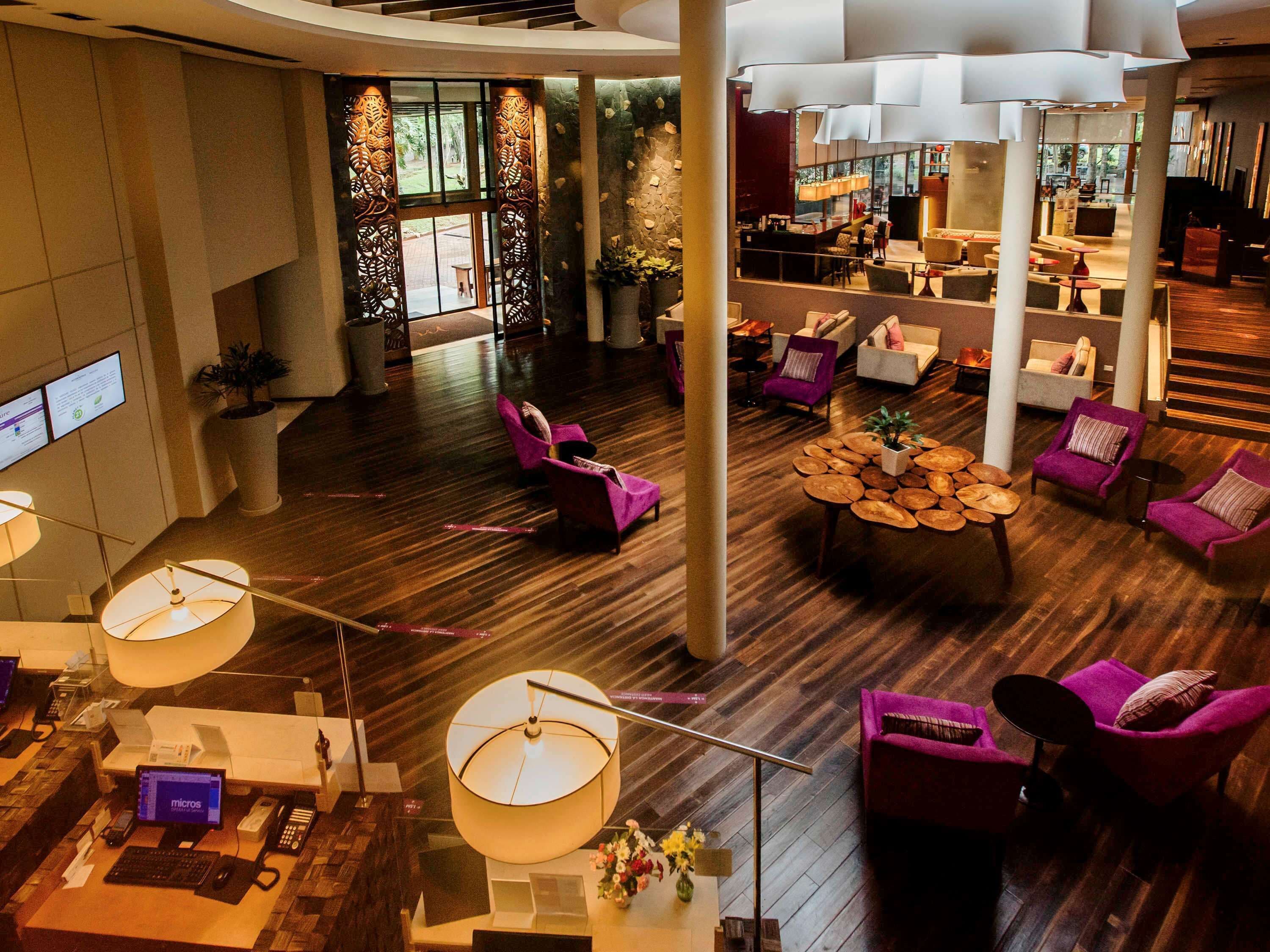 A spacious lobby with wooden flooring, purple seating, and a central coffee table.