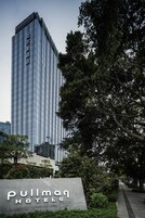 Un edificio hotelero alto y moderno con un letrero que dice "Pullman Hotels" al frente.