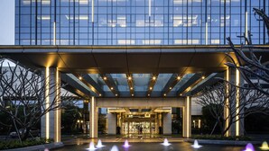 Ein moderner Hotelzugang mit Glasfassade, überdachtem Eingangsbereich und einem Wasserspiel.