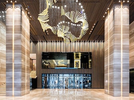 Un hall d’entrée spacieux au design moderne, agrémenté d’un grand lustre et d’une vitrine.