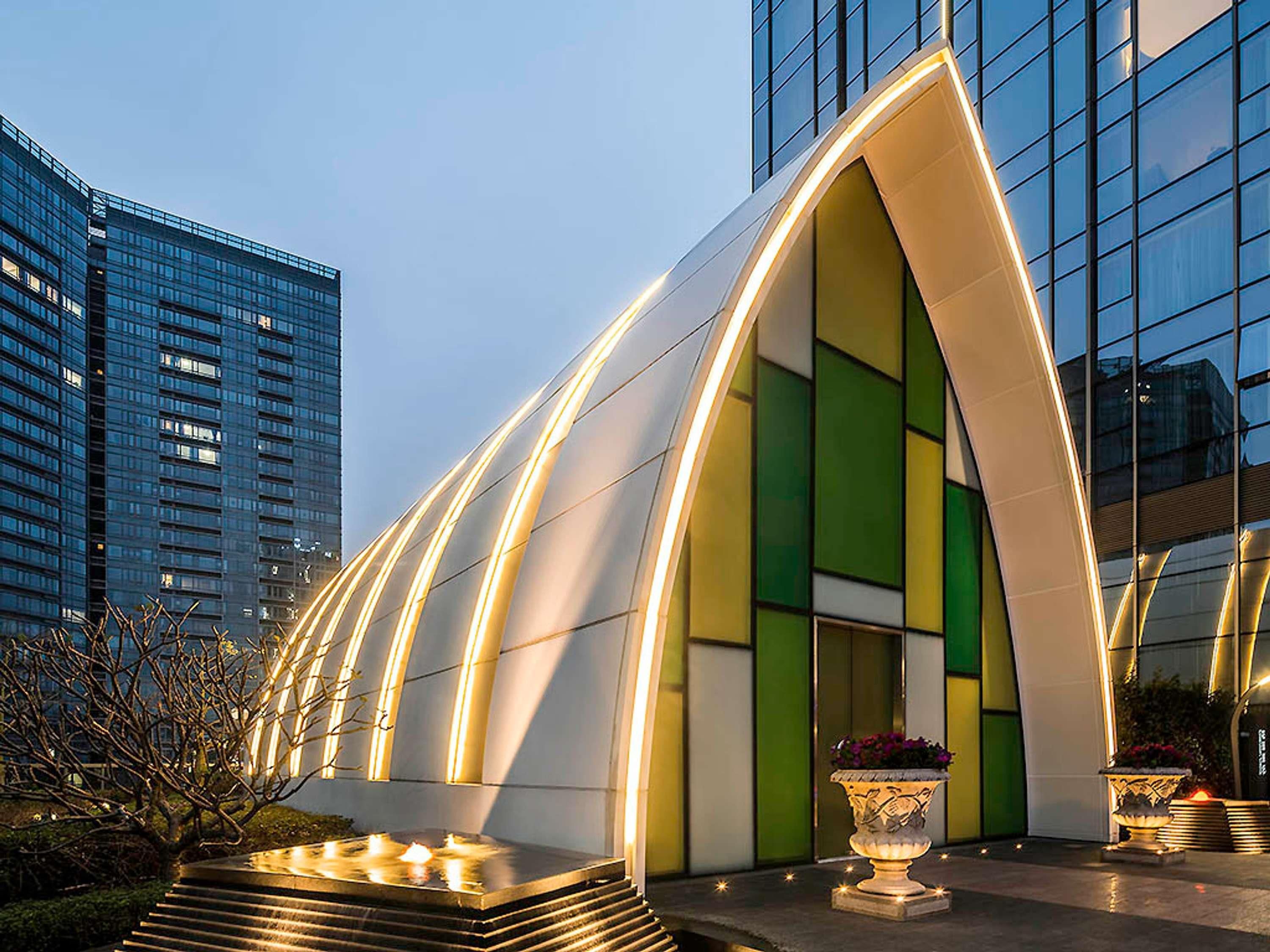 A modern building with a curved facade, large windows, and outdoor lighting.