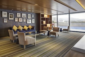 A modern lounge area with a sofa, armchairs, a coffee table, and a bookshelf. - Pullman Zhuhai (Zhuhai)