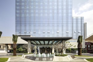 A modern building with a glass facade, a covered entrance, and a water feature in front.