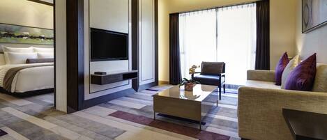 Una habitación de hotel moderna con cama, sofá, mesa de centro, televisor y una ventana grande con cortinas.