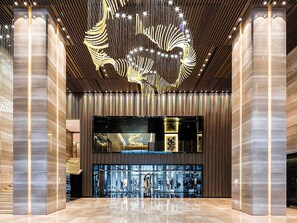A spacious lobby with a modern design, featuring a large chandelier and a glass display case. - Pullman Zhuhai (Zhuhai)