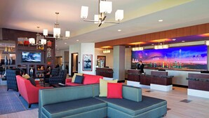 A modern lobby with a large sectional sofa, a bar area, and a large TV screen displaying a cityscape. - Residence Inn by Marriott Los Angeles LAX/Century Boulevard (Los Angeles)