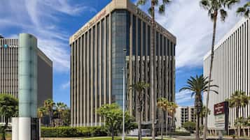 A modern hotel building with a prominent 'Residence Inn' sign, surrounded by palm trees and other buildings.