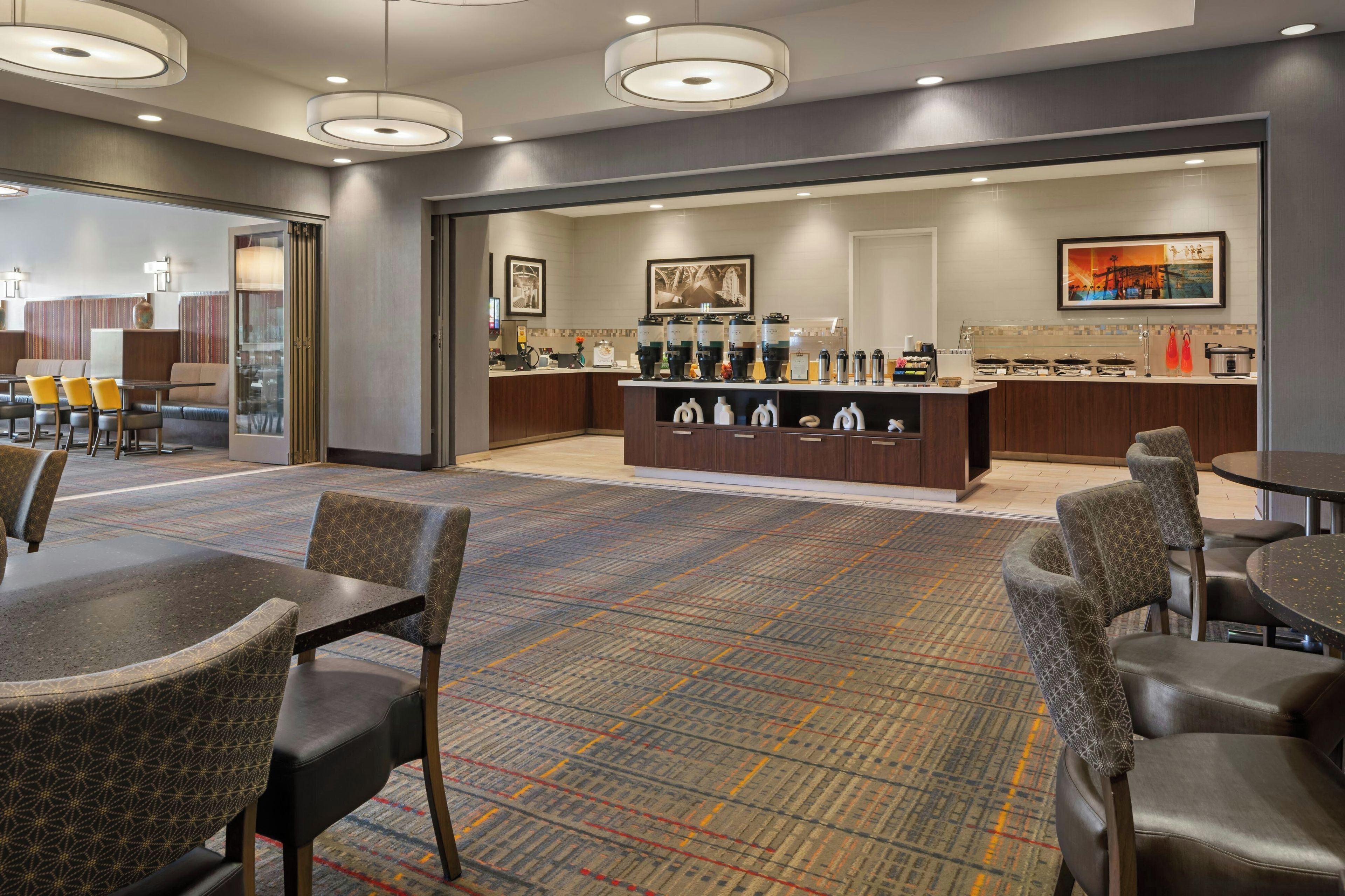 A hotel lobby with a reception desk, seating area, and a coffee bar.
