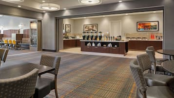 A hotel lobby with a reception desk, seating area, and a coffee bar.