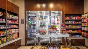 A grocery store interior with refrigerated sections, snack aisles, and baskets of snacks. - Residence Inn by Marriott Los Angeles LAX/Century Boulevard (Los Angeles)