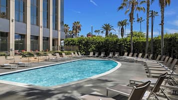A swimming pool with lounge chairs and palm trees.