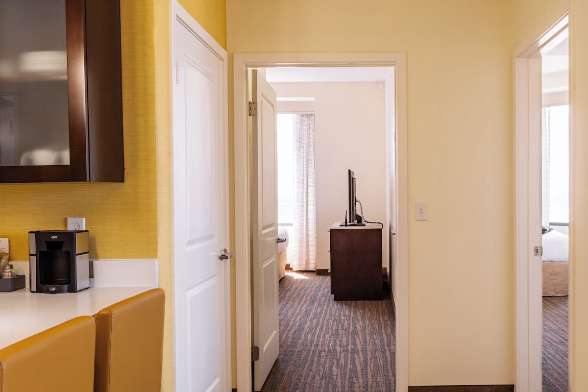 A hotel hallway with a coffee machine, a desk, and a television.