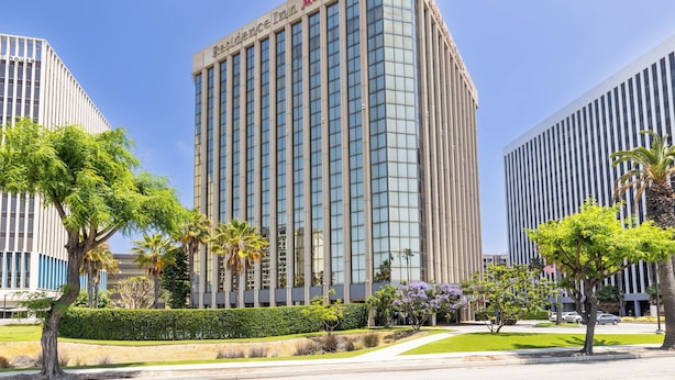 A tall hotel with a clear sky, surrounded by greenery and other buildings. - Residence Inn by Marriott Los Angeles LAX/Century Boulevard (Los Angeles)