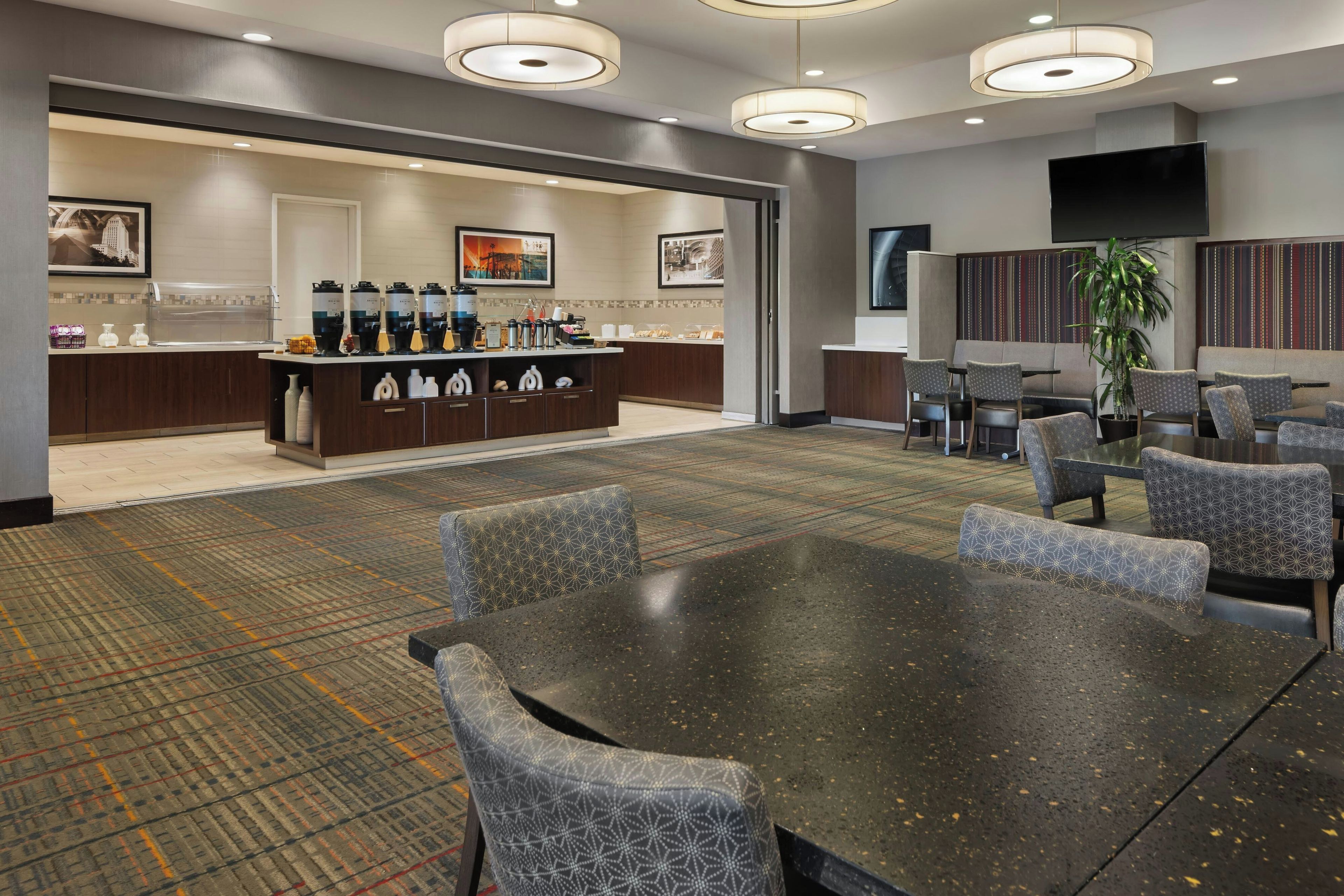 A hotel lobby with a reception desk, seating area, and a large screen.