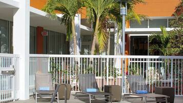 A pool area with lounge chairs and palm trees, surrounded by a white fence.