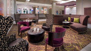 A spacious lobby with patterned armchairs, a sofa, and a coffee table, featuring a stone wall and a television in the background. - Residence Inn by Marriott West Palm Beach Downtown (West Palm Beach)