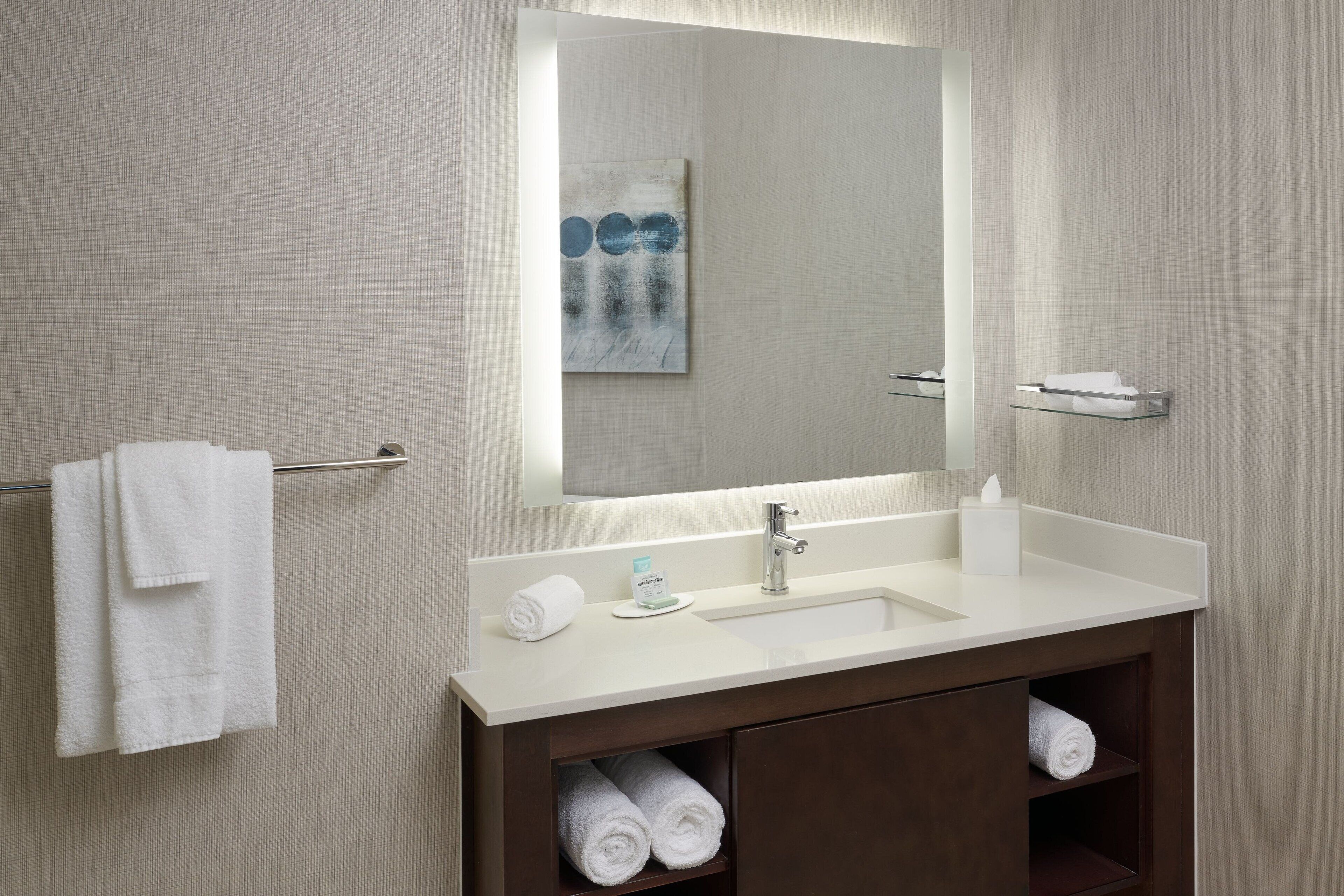 A modern bathroom with a white sink, a mirror, and a towel rack.