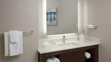 A modern bathroom with a white sink, a mirror, and a towel rack.