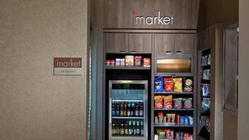 A hotel market area with a refrigerated section and shelves stocked with snacks.