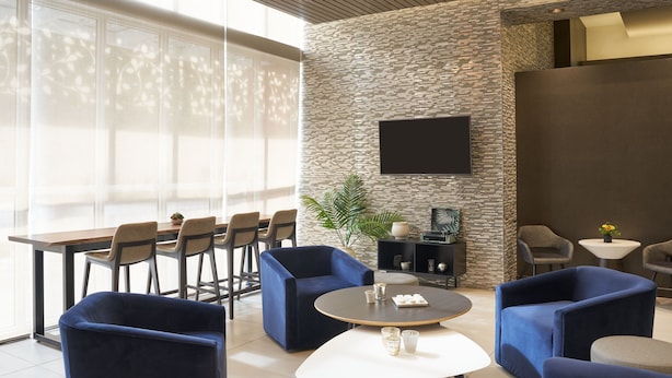 A modern lounge area with a stone wall, a flat-screen TV, and comfortable seating including sofas and chairs. - Residence Inn by Marriott West Palm Beach Downtown (West Palm Beach)