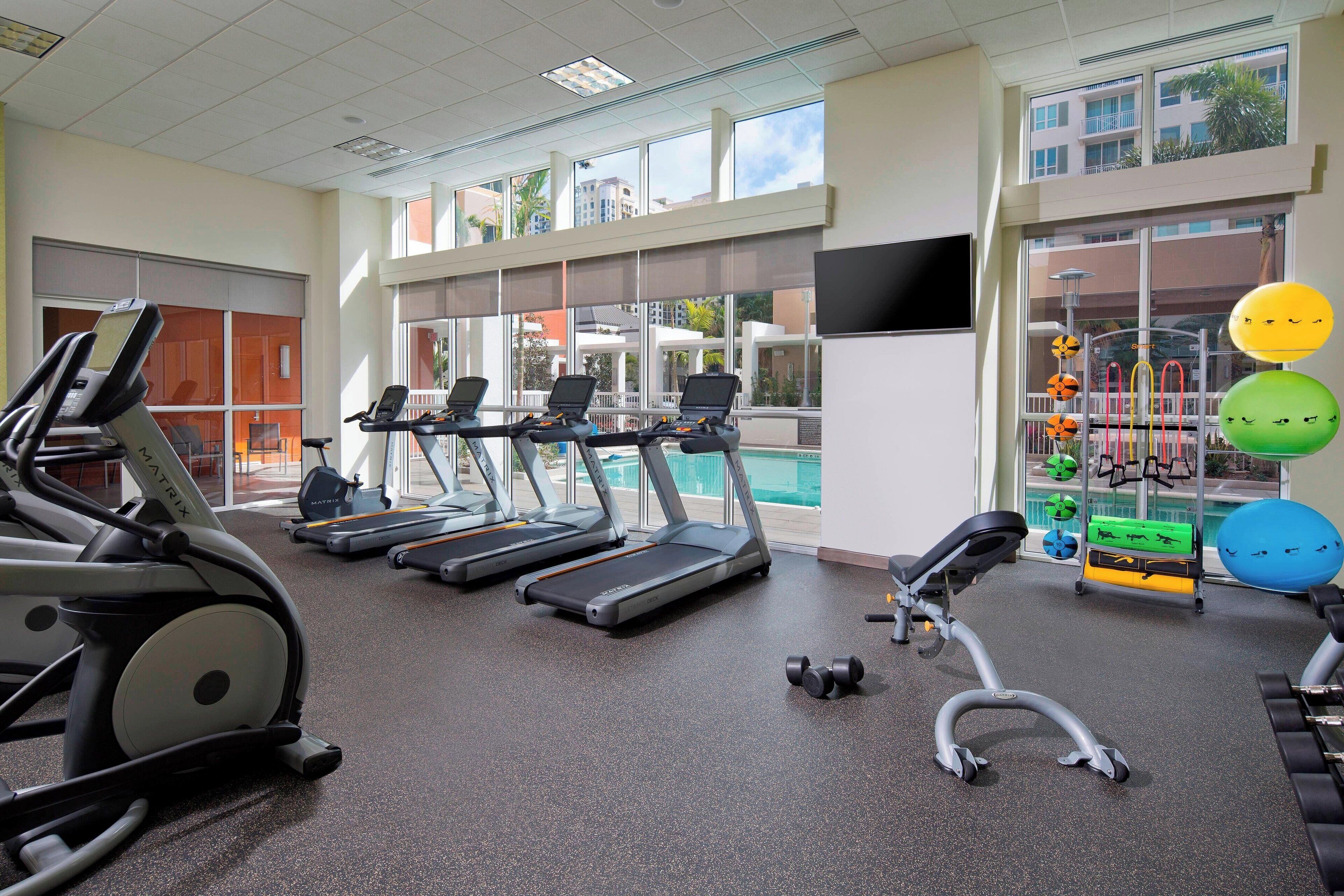 A gym with treadmills, dumbbells, and exercise balls.