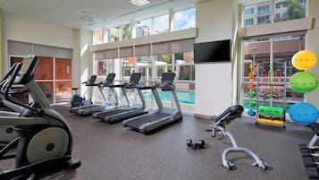 A gym with treadmills, dumbbells, and exercise balls.