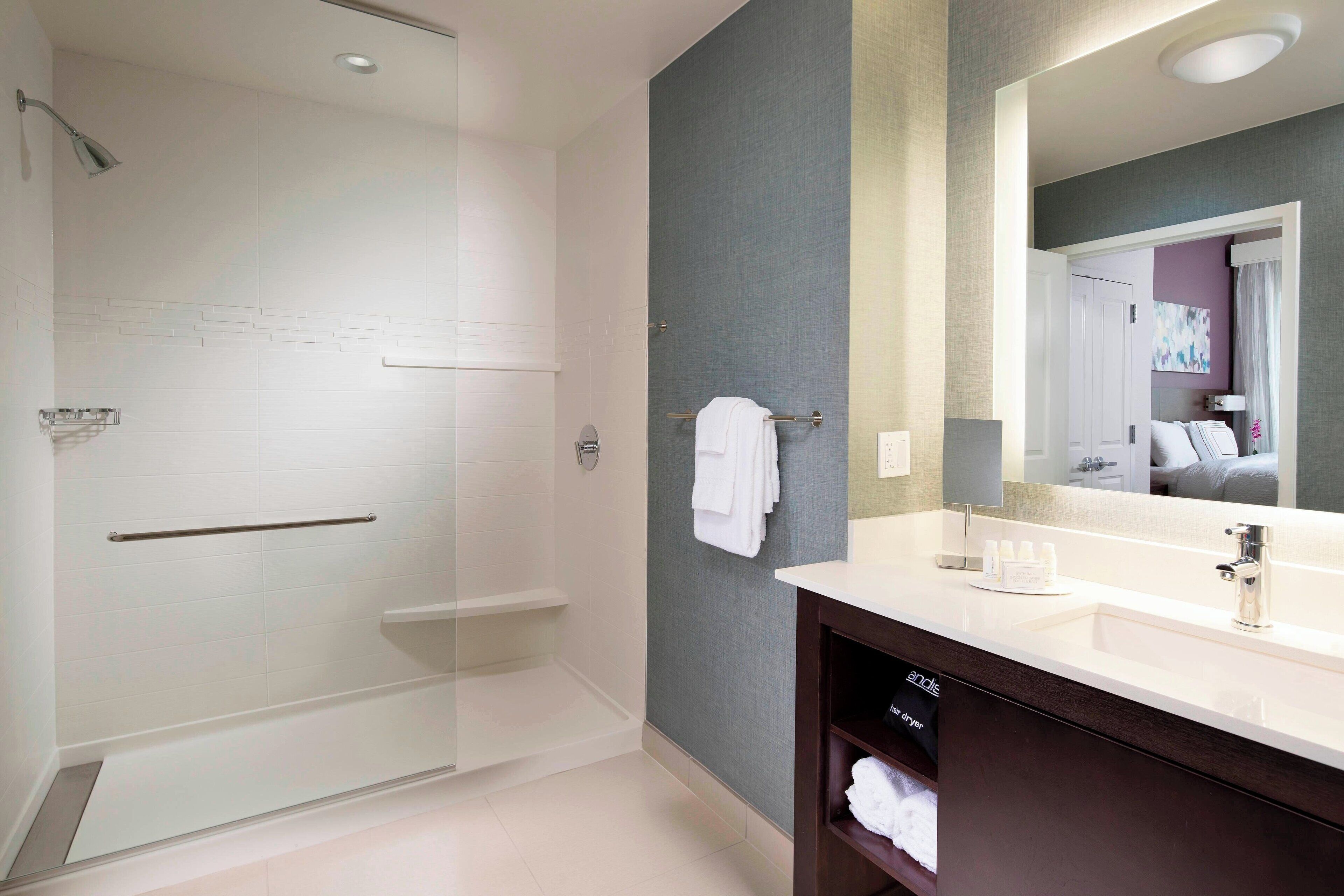 A modern bathroom with a glass shower enclosure, a vanity with a mirror, and a towel rack.