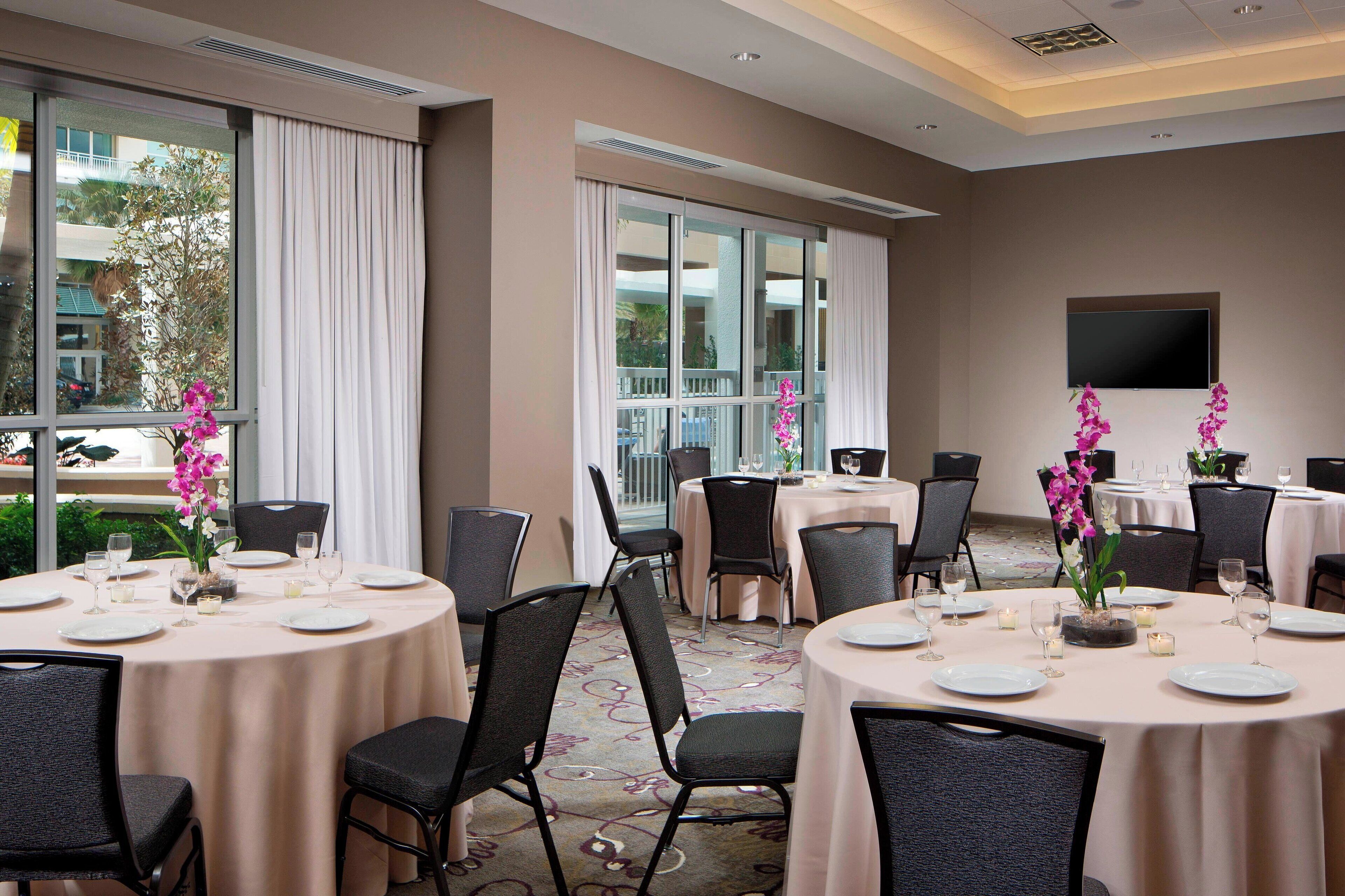 A conference room with round tables, chairs, and floral centerpieces.